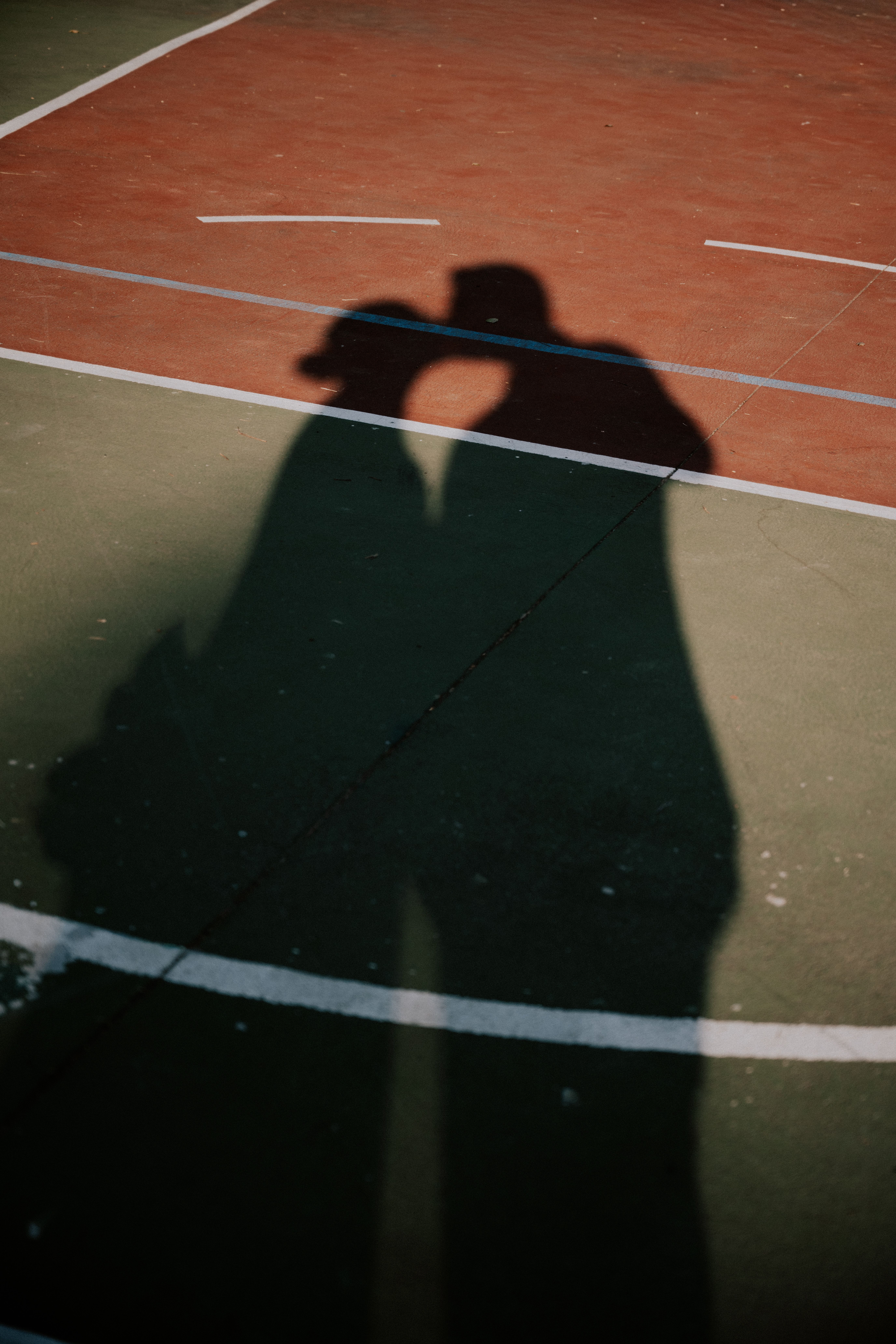 Shadow of a couple kissing on a colorful basketball court in Çanakkale, Türkiye.