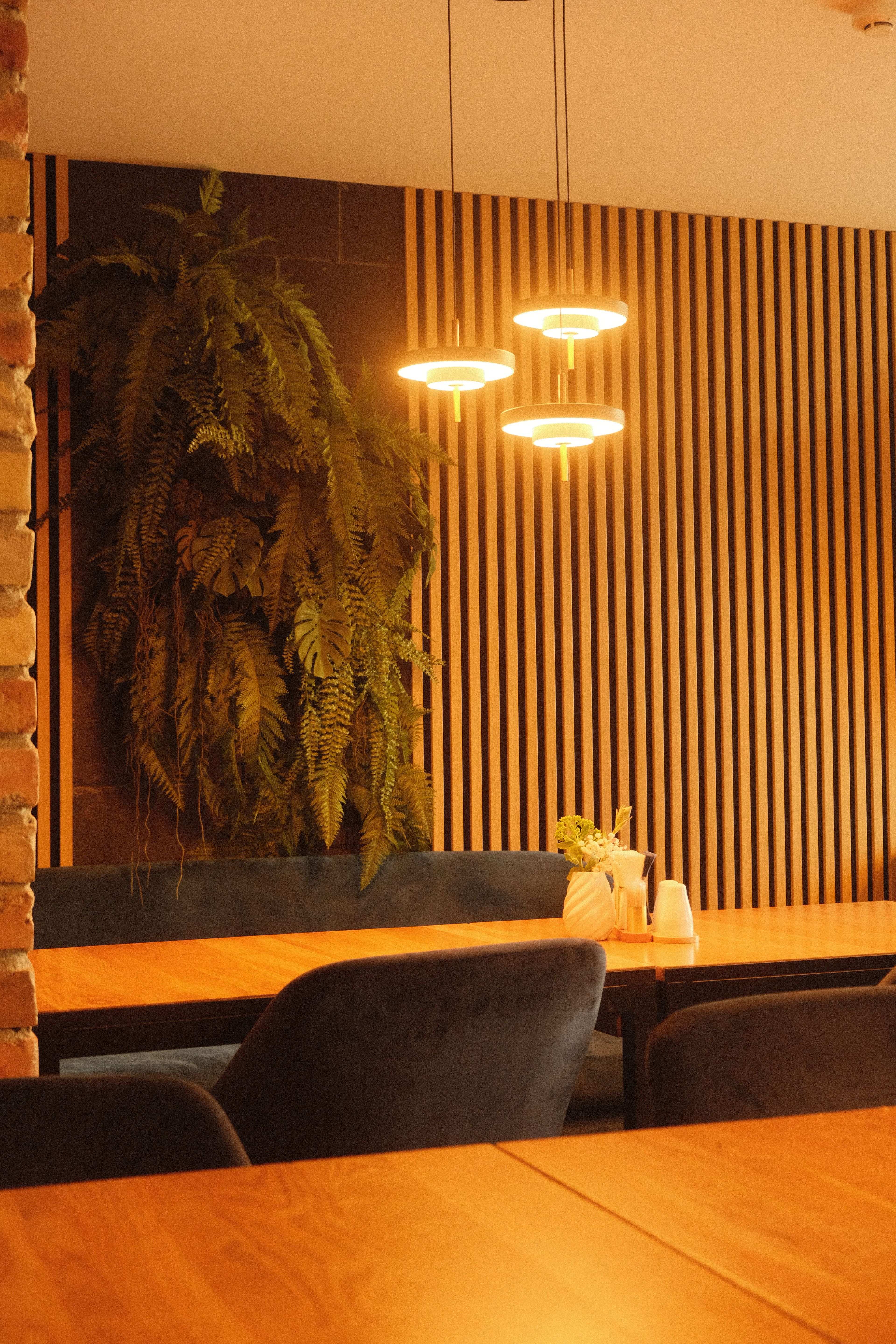 Warm café interior with vertical timber slat wall panels and pendant lighting