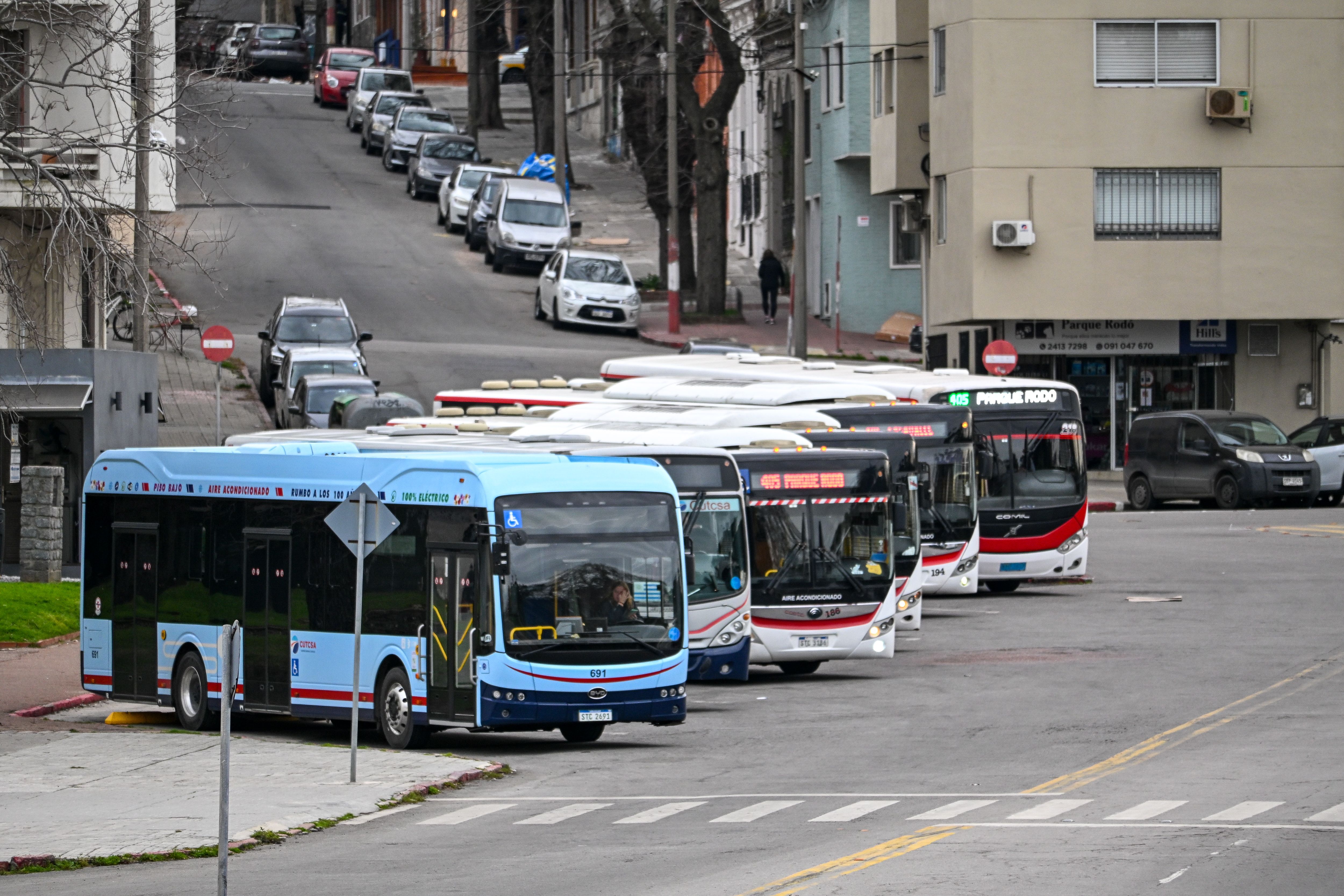 Public buses lined up on a cloudy city street in Montevideo.