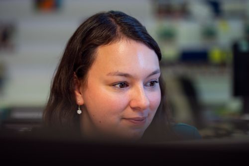 Free A professional woman concentrates on her computer screen in a busy office environment. Stock Photo