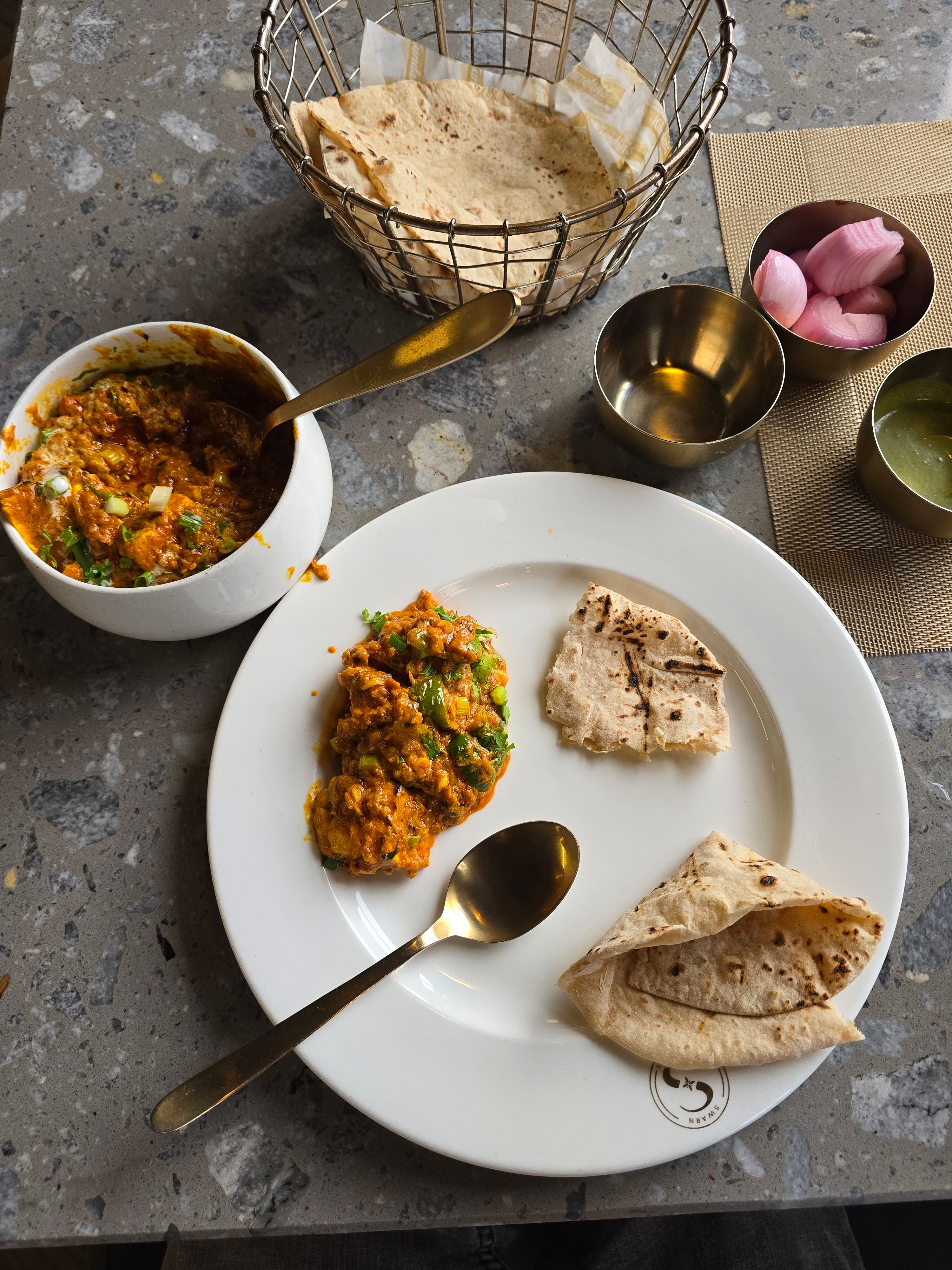 Top view of Indian roti with curry and sides on a rustic table.