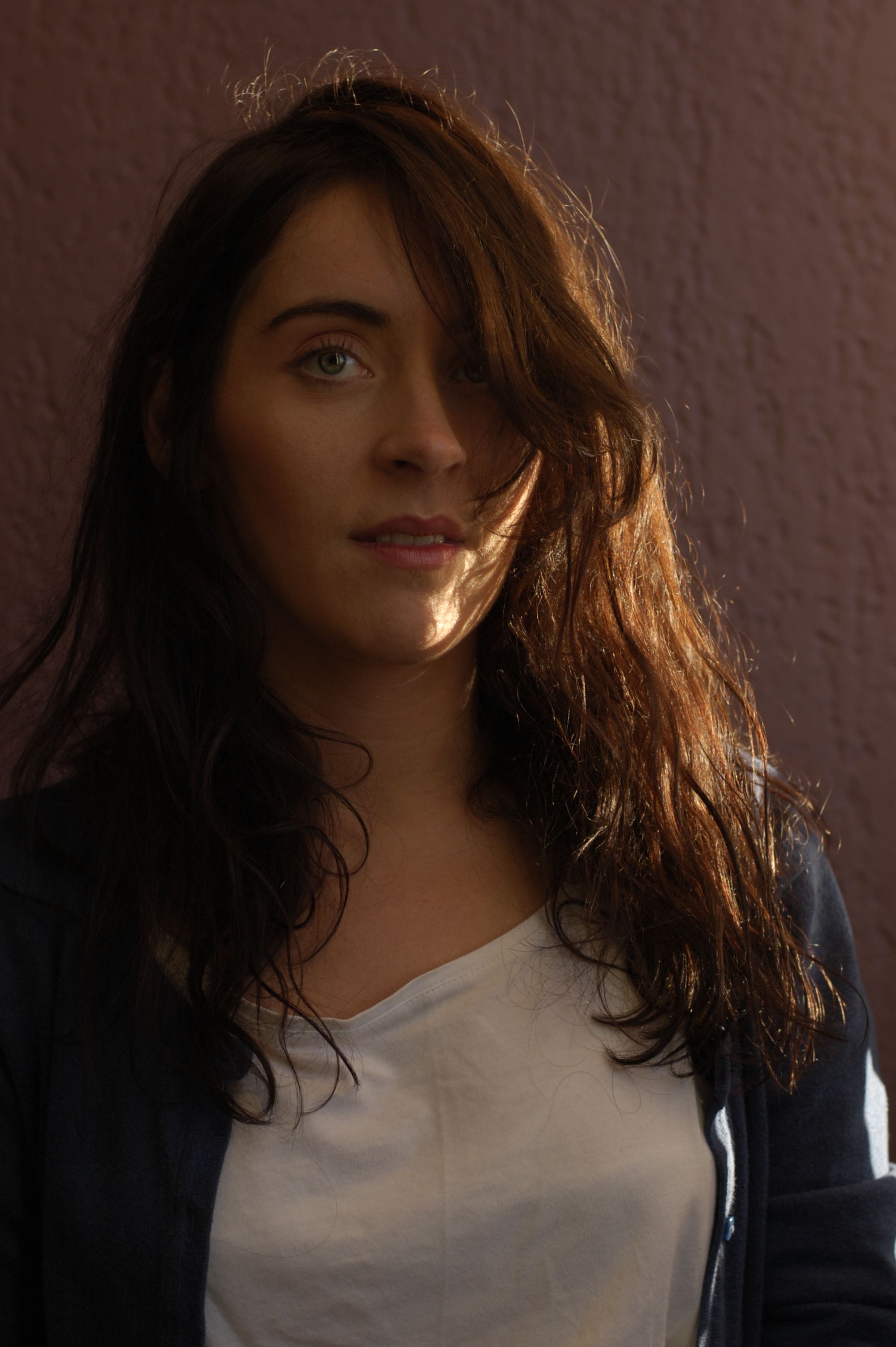 Portrait of a woman with side lighting, casting shadows indoors.