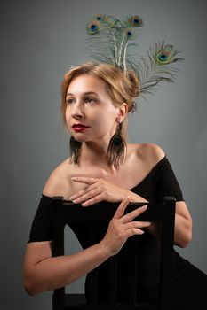 Portrait of a woman in black dress with peacock feather accessories, showcasing elegance and style.