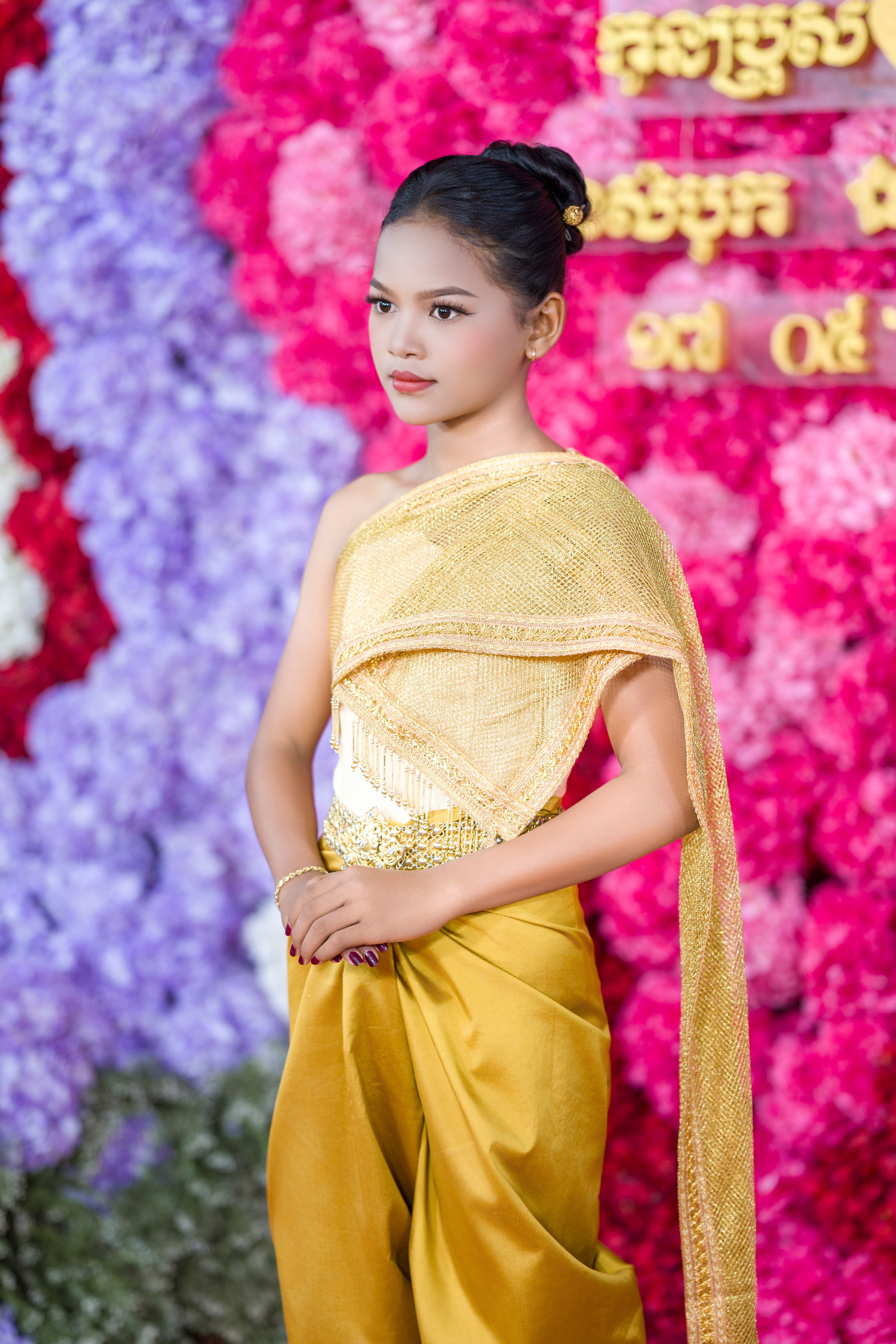 A woman in traditional Cambodian attire at a vibrant cultural ceremony, showcasing elegance and tradition.