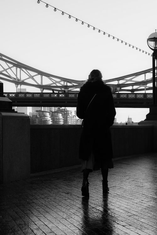 Free Black and white image of a woman silhouetted on London's Tower Bridge at dusk. Stock Photo