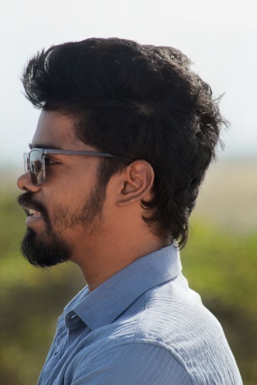 Free Side profile portrait of a young man wearing sunglasses outdoors on a sunny day. Stock Photo
