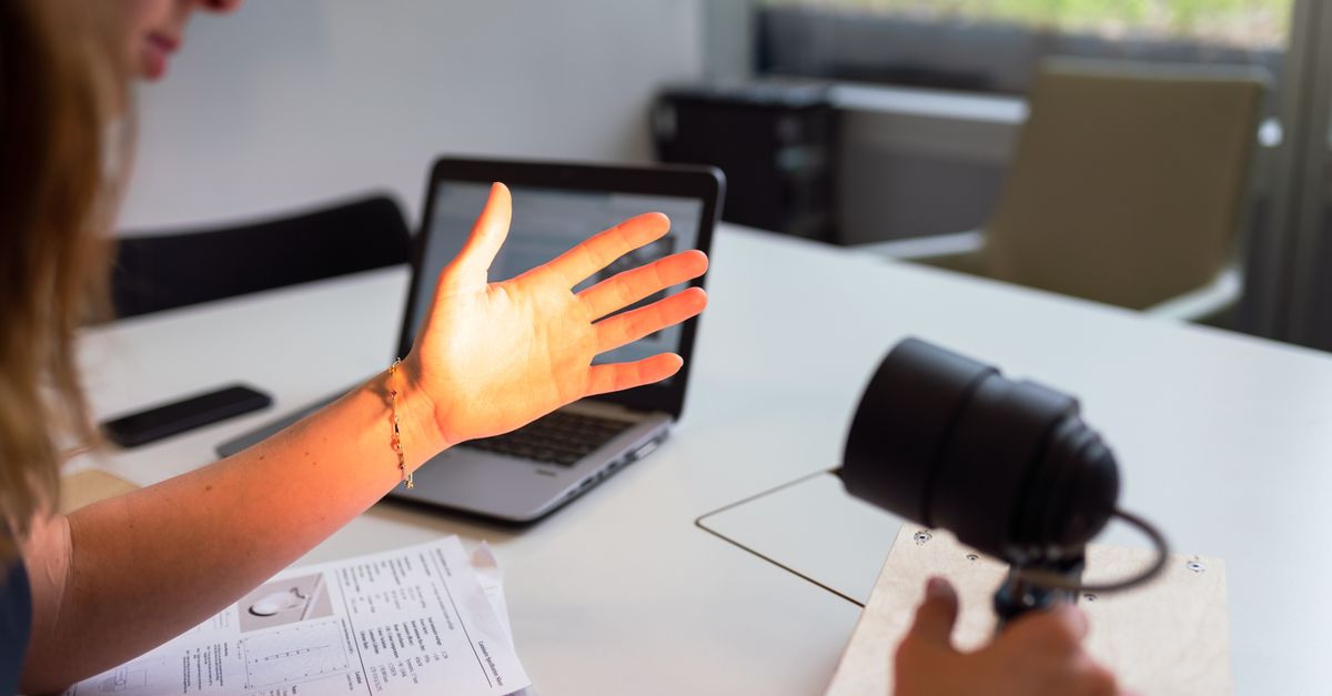 Female engineer tests lighting prototype on her hand in a modern office environment.