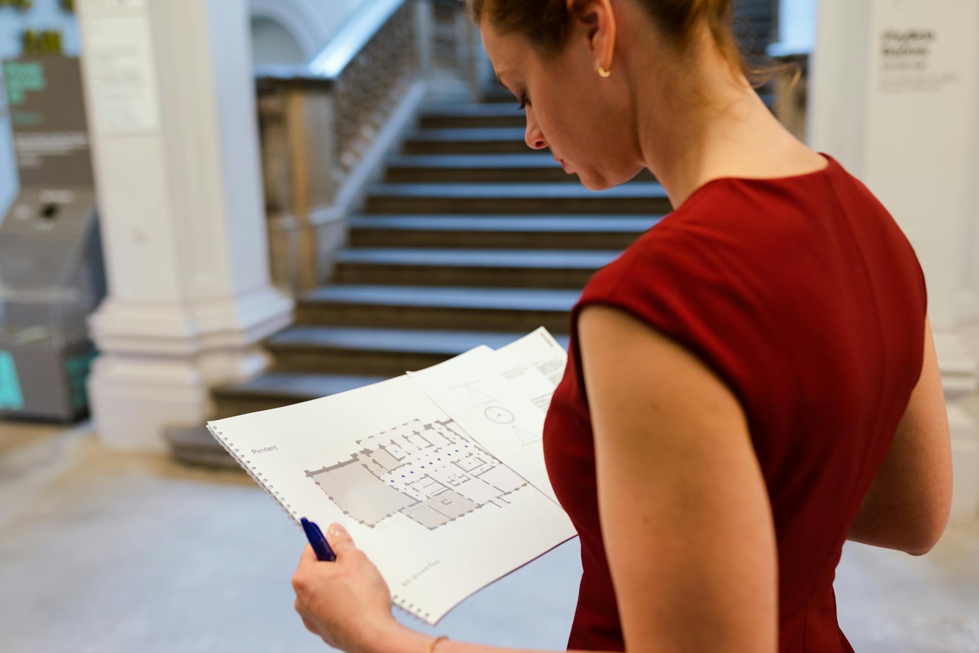 A professional woman examines an architectural floor plan in an indoor setting.