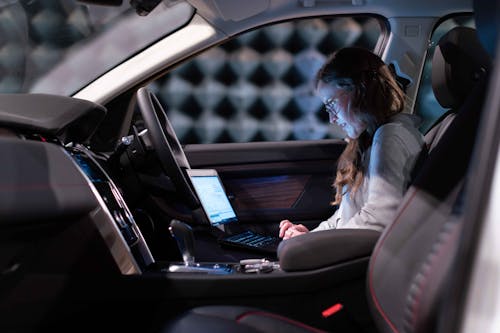 Free Female Engineer using Laptop Inside a Car  Stock Photo
