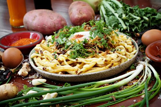 A savory Spätzle dish garnished with herbs and surrounded by fresh vegetables and spices.
