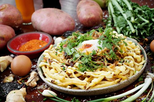 Free Delicious gourmet loaded fries topped with an egg, herbs, and spices, surrounded by fresh ingredients. Stock Photo