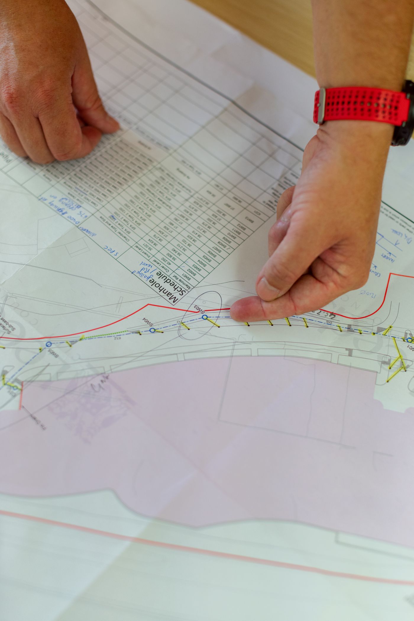 Engineer's hands pointing at an architectural blueprint during construction planning, close-up