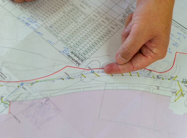 Hands reviewing architectural blueprints for construction planning