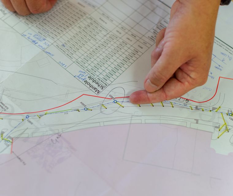 Engineer pointing at a marked-up plan on a desk