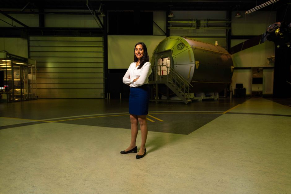 emotional intelligence in leadership - A professional female engineer stands confidently in a spacecraft hangar, showcasing intelligence and pride.