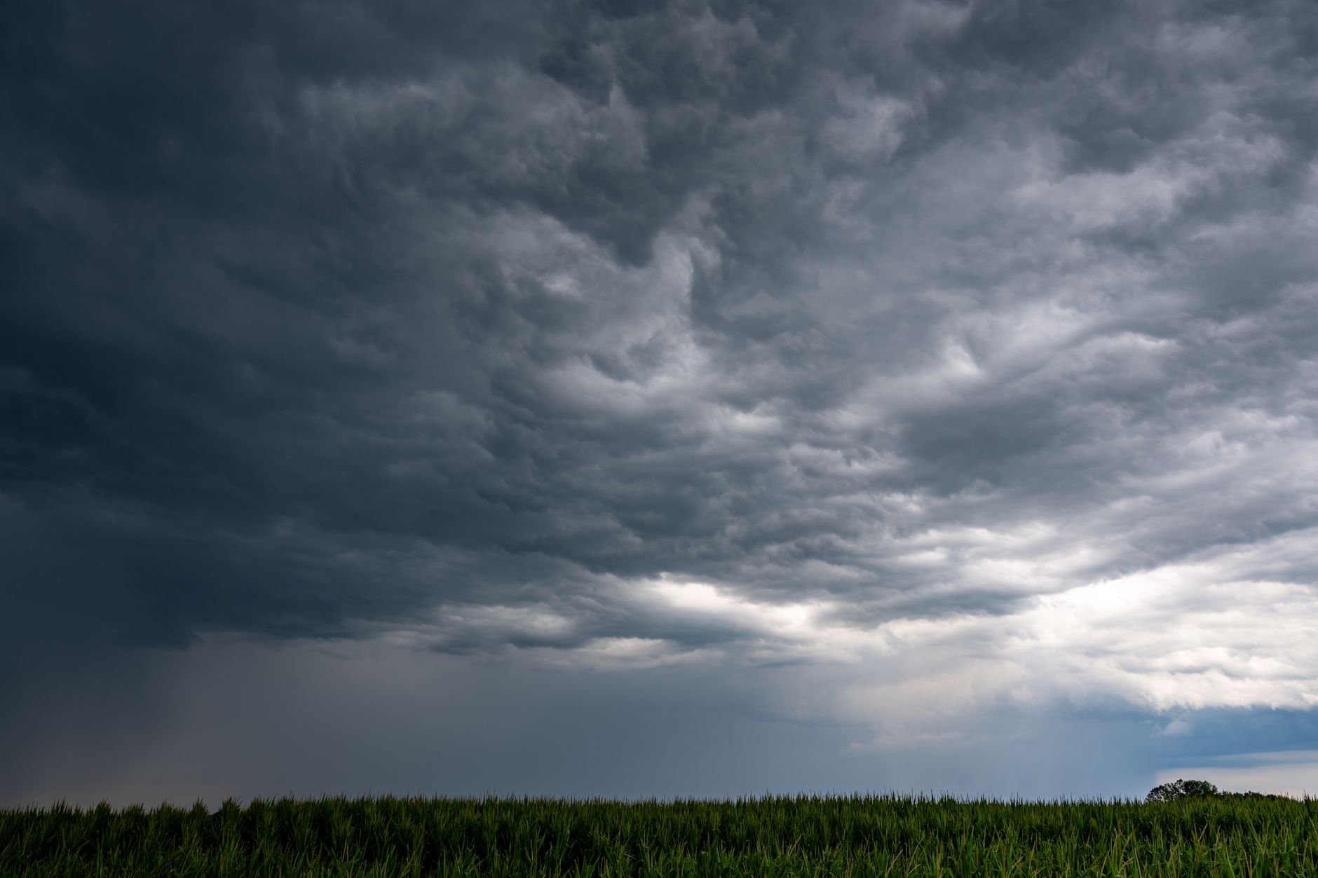 A dramatic cloudy sky over a green field in Garešnica, Croatia, capturing a moment of impending storm.