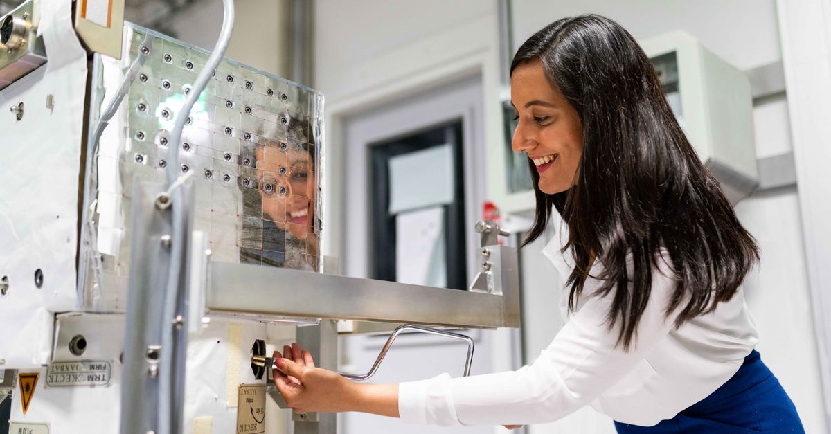 A female engineer operating machinery in a laboratory setting with a reflective surface.