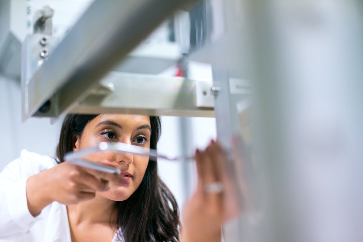 A professional working carefully with equipment in a laboratory.