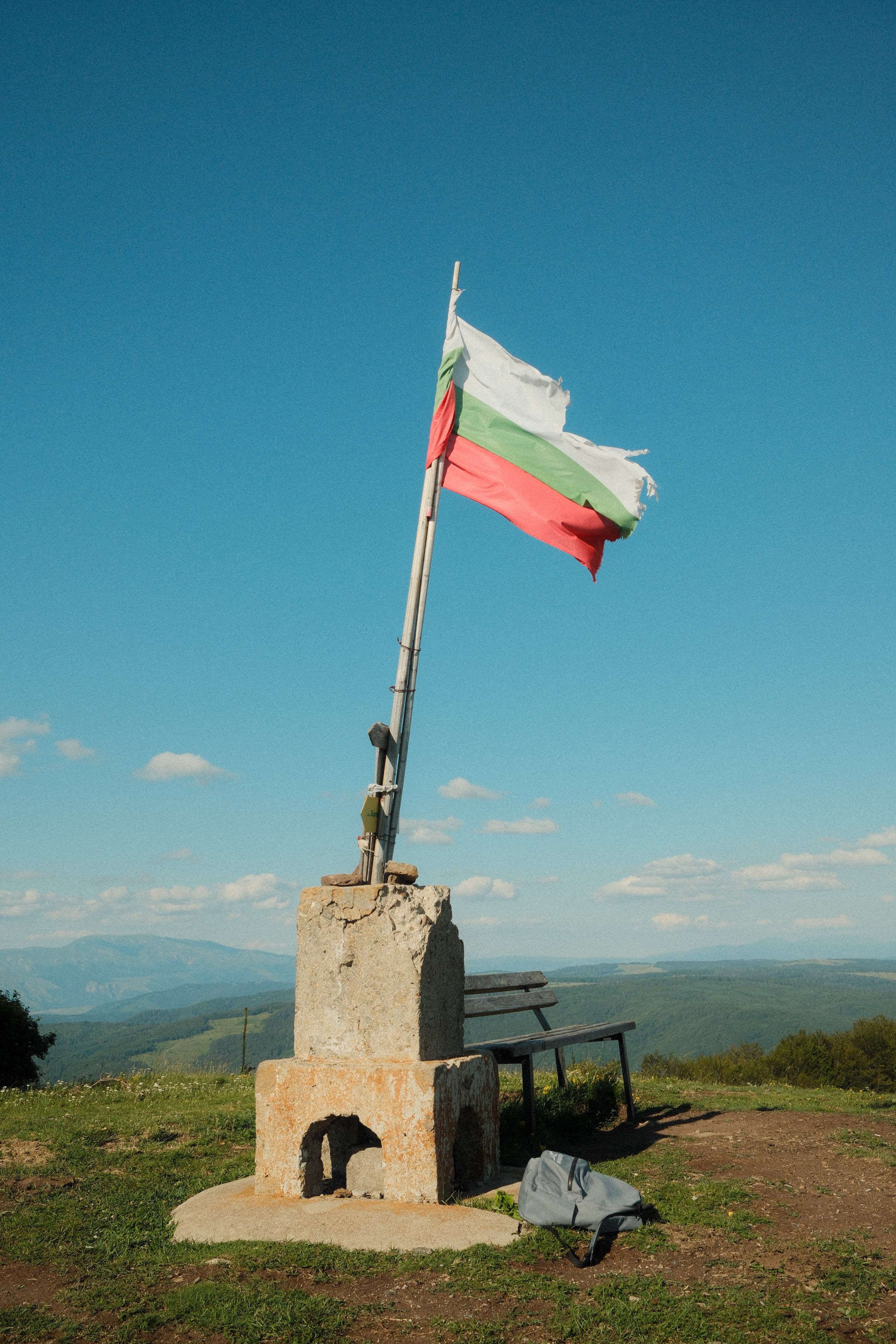 Fotomural Una bandera búlgara se alza en la cima de una montaña en un día despejado, simbolizando el orgullo nacional.