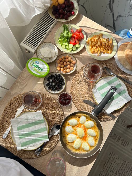 Free A vibrant Turkish breakfast spread featuring eggs, vegetables, and tea in a sunlit room. Stock Photo