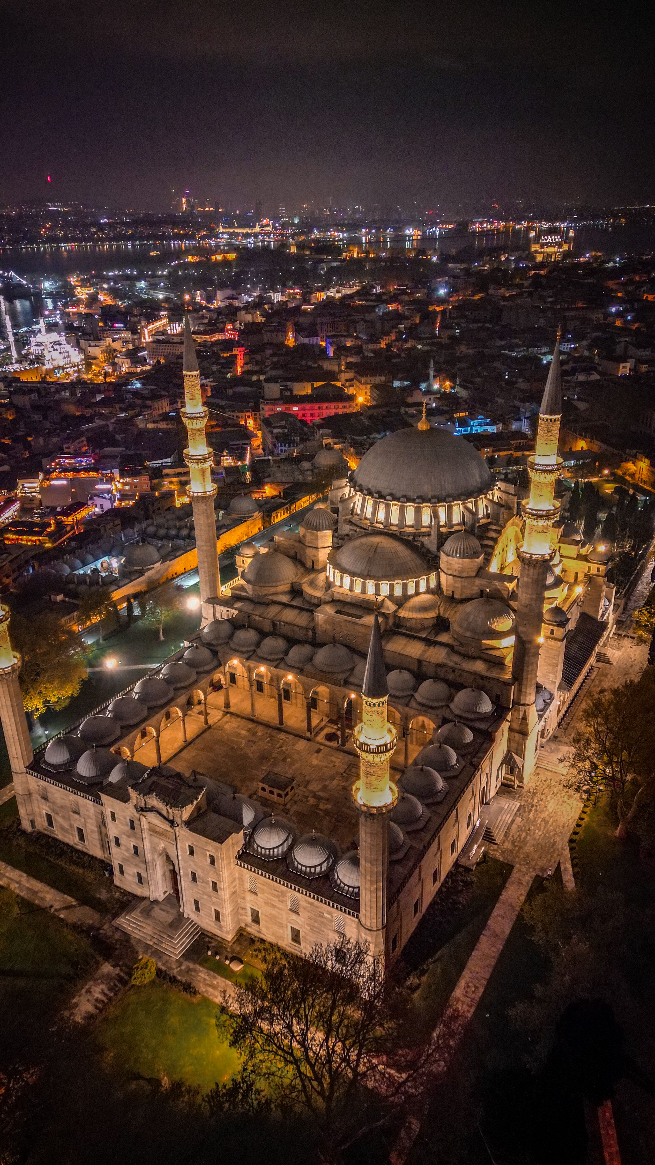 Stunning aerial photograph of the illuminated Suleymaniye Mosque at night overlooking Istanbul's cityscape.