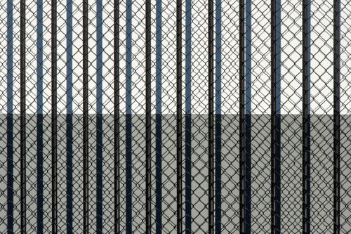 Free Artistic abstract image of a chain link fence casting shadows creating geometric patterns. Stock Photo