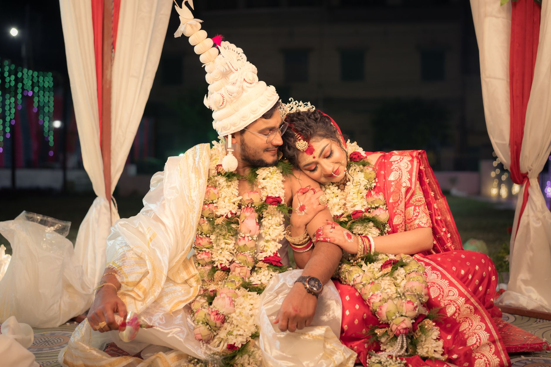 A beautiful Bengali couple on their wedding day, adorned with floral garlands and traditional attire.