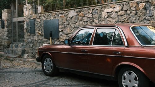 Free Classic vintage car parked by a rustic stone wall, showcasing nostalgic style. Stock Photo