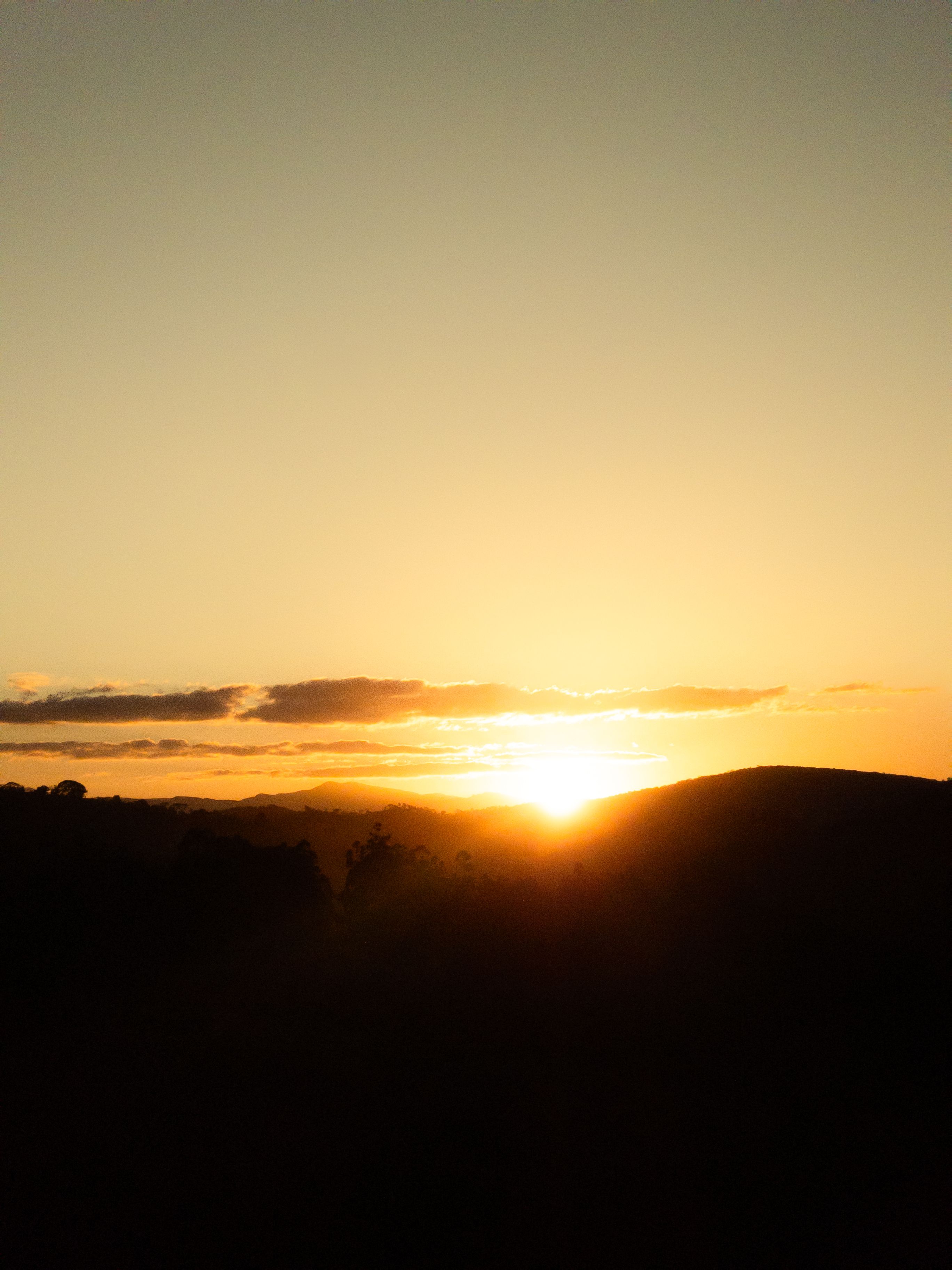 Peaceful sunset casting a golden glow over the hills in Rio Vermelho, Brazil.