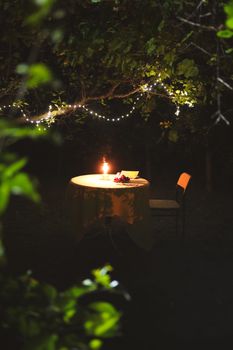 Intimate outdoor candlelit dinner table in a serene garden ambiance.