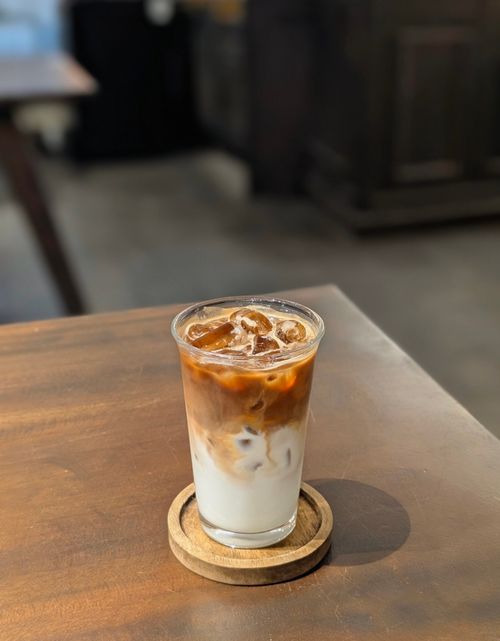 Free A refreshing glass of iced coffee served on a wooden table in a cozy indoor setting. Stock Photo