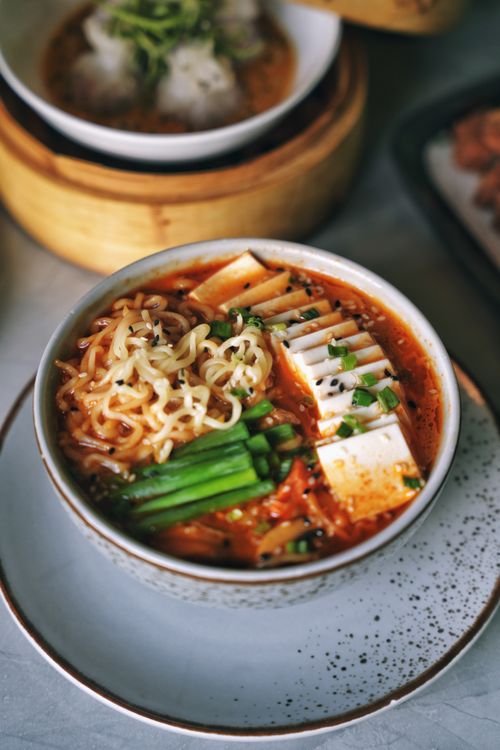 Free Mouth-watering spicy ramen noodle bowl garnished with tofu, vegetables, and spices. Stock Photo