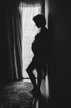 阳光明媚的窗户旁，一位孕妇的轮廓平静而沉思