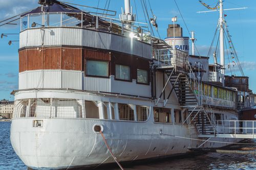 Free A vintage boat moored near a city harbor under a clear blue sky. Stock Photo