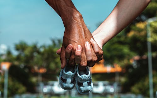 Free A Couple Holding Hands With A Toddler's Shoes Stock Photo