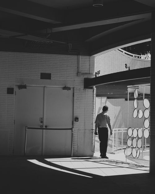 Free Silhouetted man walks in geometric shadows inside a modern building in Taiwan. Stock Photo