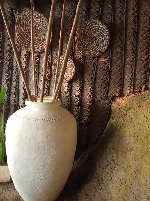 Free A rustic interior featuring a clay pot with bamboo sticks against a woven wall. Stock Photo