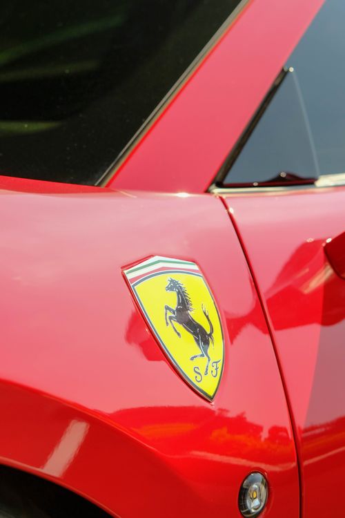 Free Bright red sports car emblem in focus capturing luxury and speed. Stock Photo