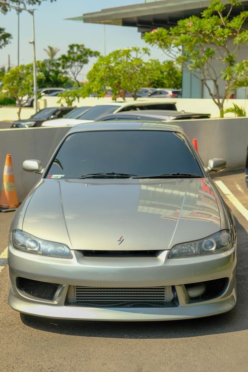 Free Front view of a silver sports car parked outdoors on a sunny day. Stock Photo