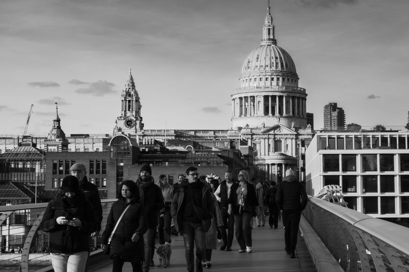 Black and white photo of people on Millennium Bridge with St. Paul's Cathedral in the background.