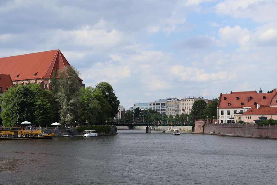 Picturesque riverside view of Wrocław with historic and modern architecture under a blue sky.