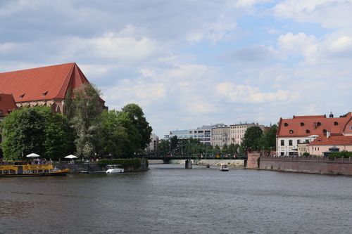 Free Picturesque riverside view of Wrocław with historic and modern architecture under a blue sky. Stock Photo