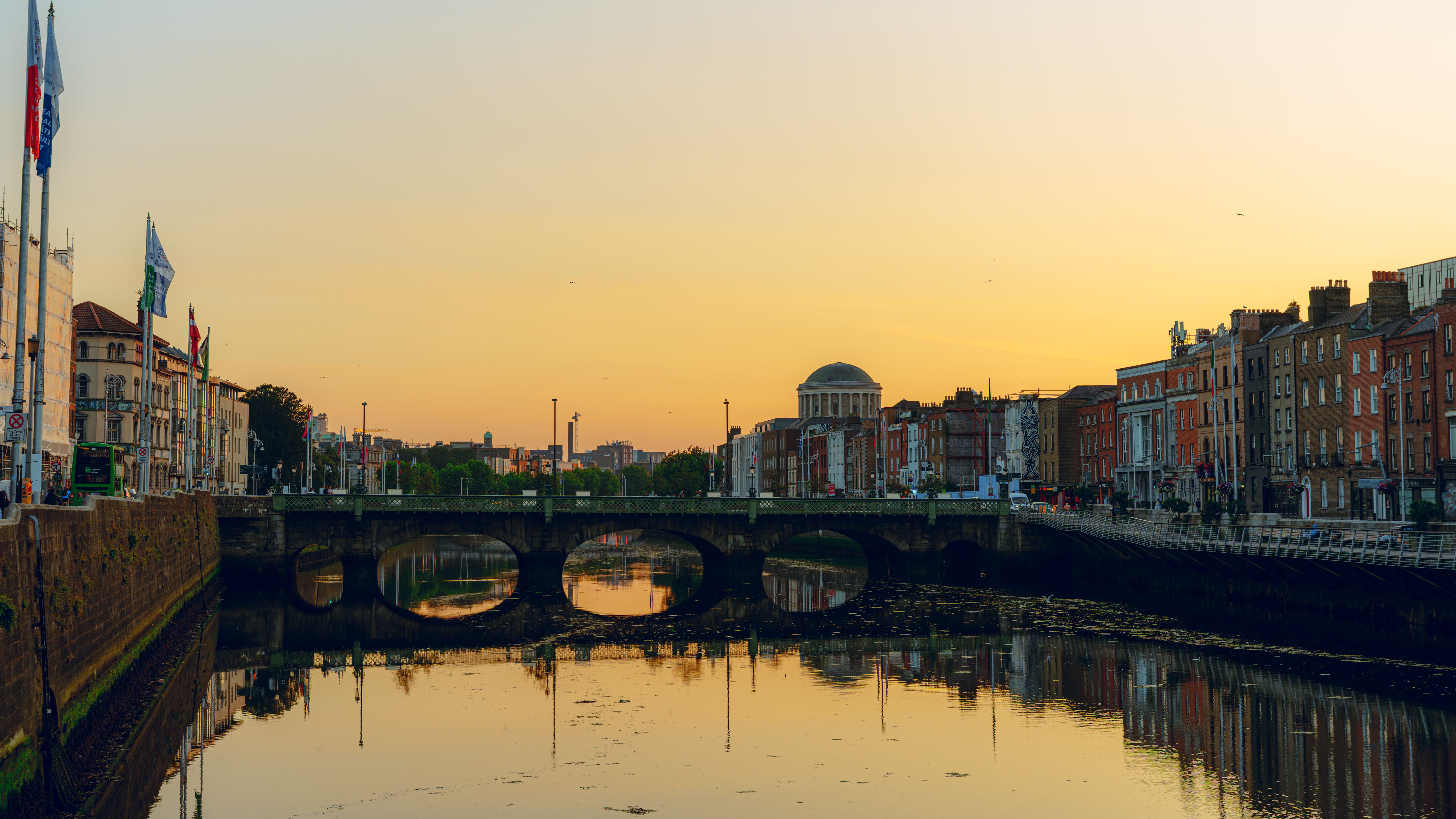 Stunning sunset view of Dublin's riverfront featuring the historic Four Courts and city architecture reflected in the water.