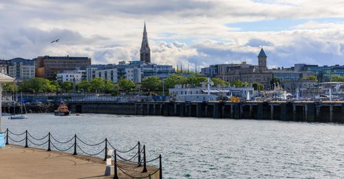 Free Beautiful summer view of Dun Laoghaire harbor with cityscape and church spire under a cloudy sky. Stock Photo
