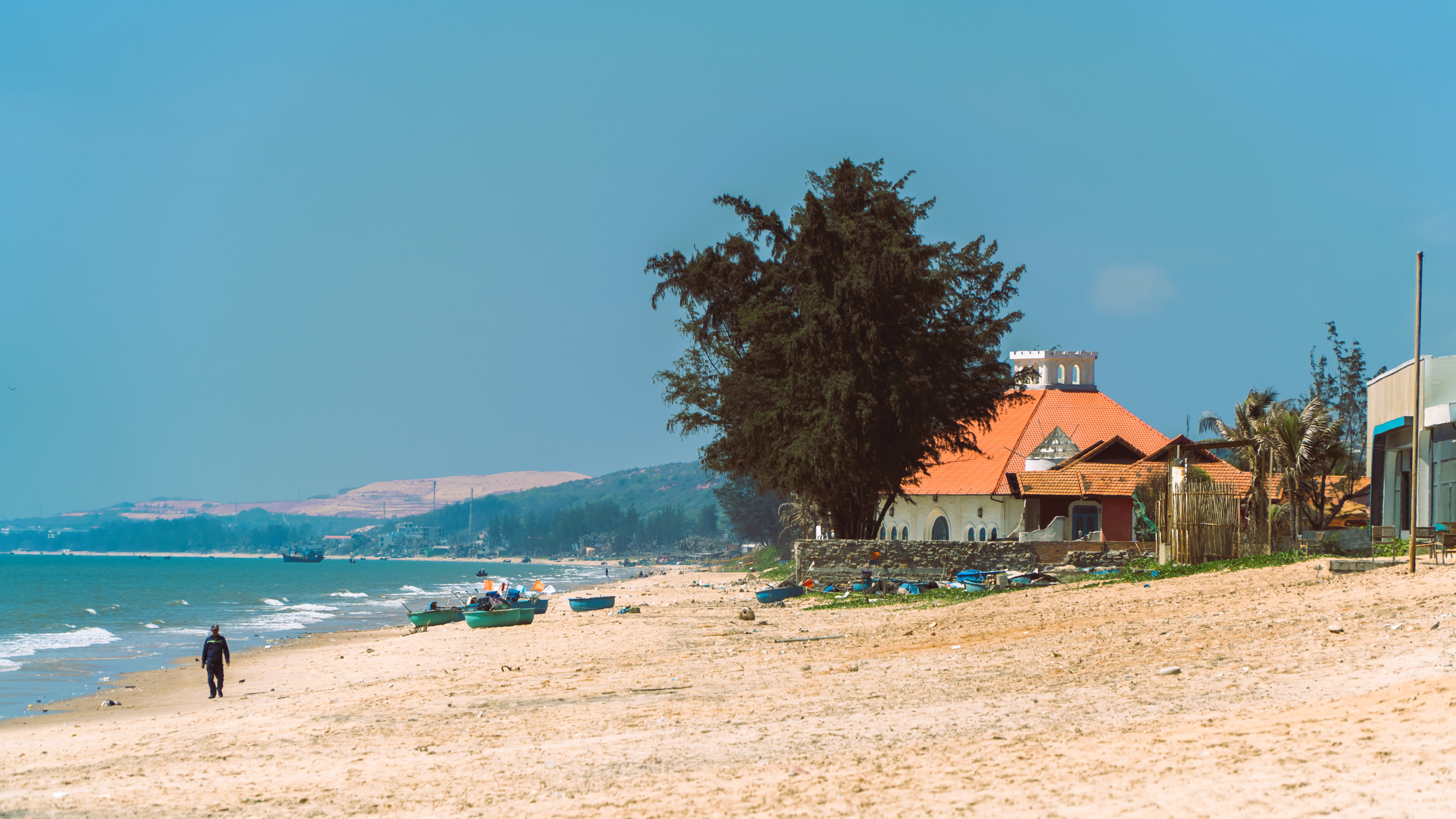 Serene beach scene with a historic church and fishing boats in Vietnam.