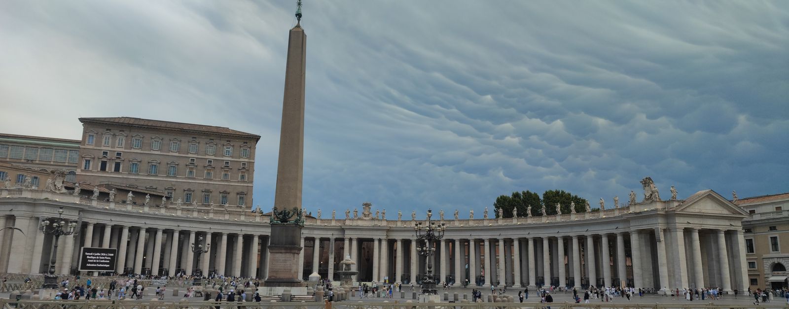 View of St. Peter's Square in Vatican City under dramatic cloud formations.