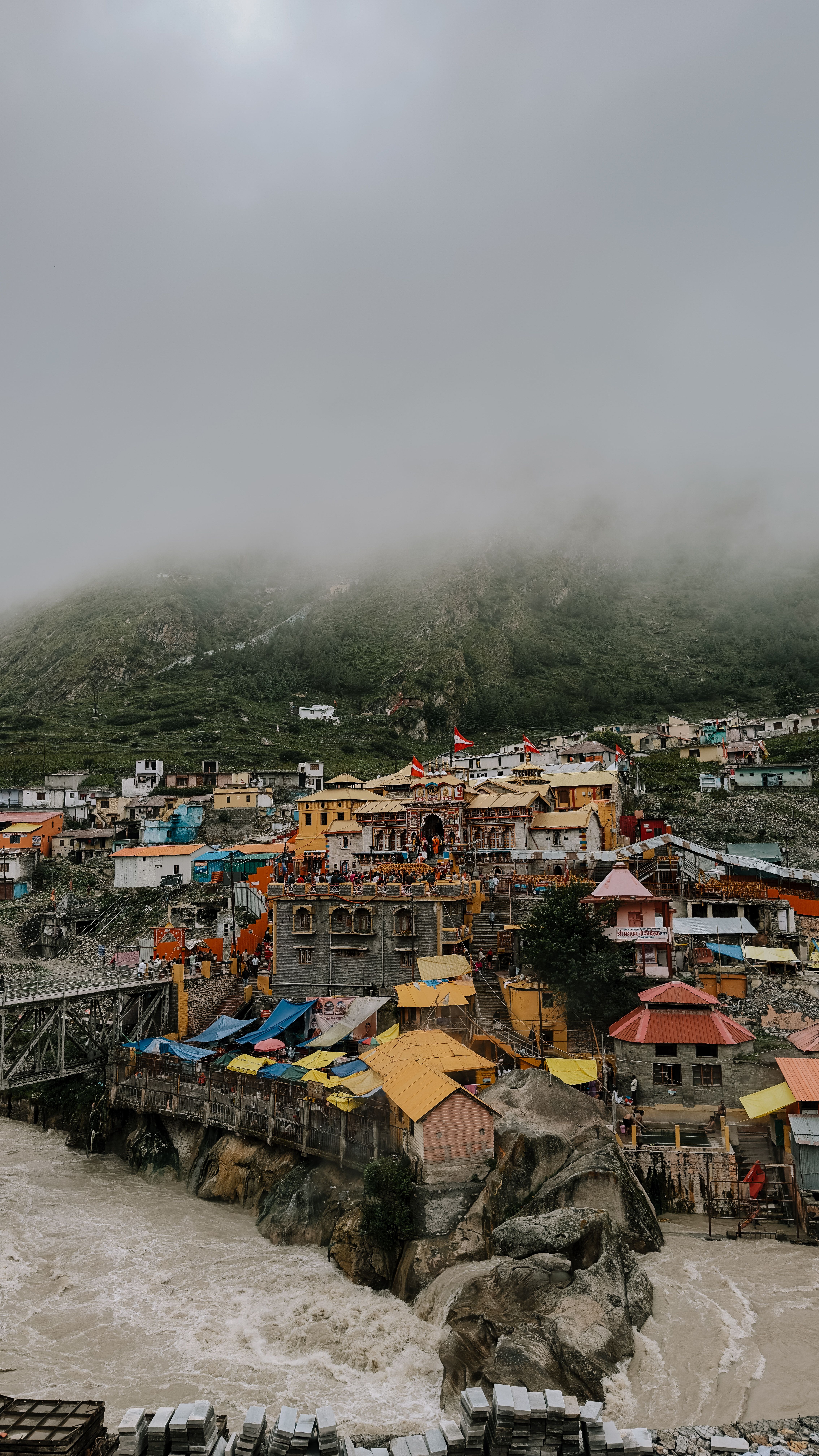 A picturesque view of Badrinath Temple surrounded by the Himalayas shrouded in mist, conveying a serene atmosphere.