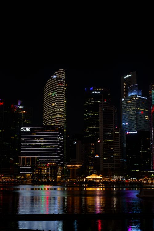 Free Vibrant night scene of Singapore skyline with lively reflections on the waterfront, showcasing modern architecture. Stock Photo