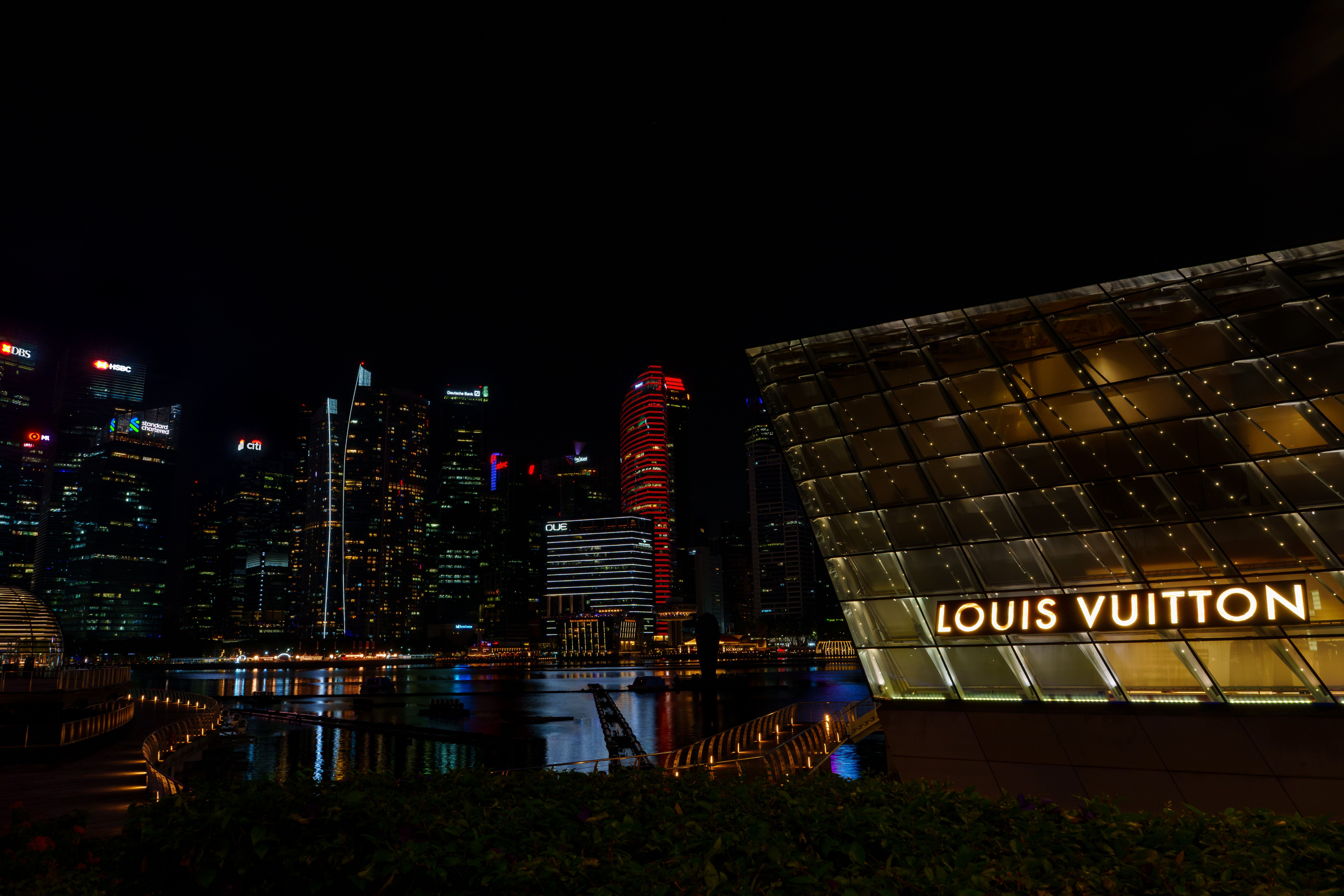 Dazzling Singapore skyline at night showcasing iconic Louis Vuitton store illuminated against skyscrapers.