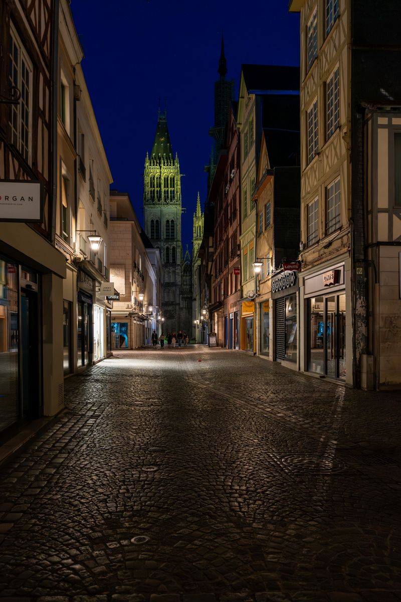 Evening street view leading to Rouen Cathedral beautifully illuminated at dusk in Normandy